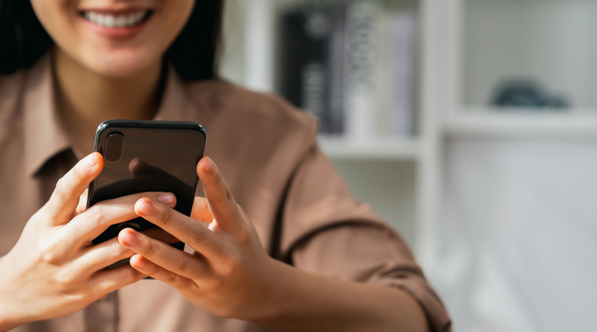 Smiling young woman hand holding smartphone with using social media on internet.